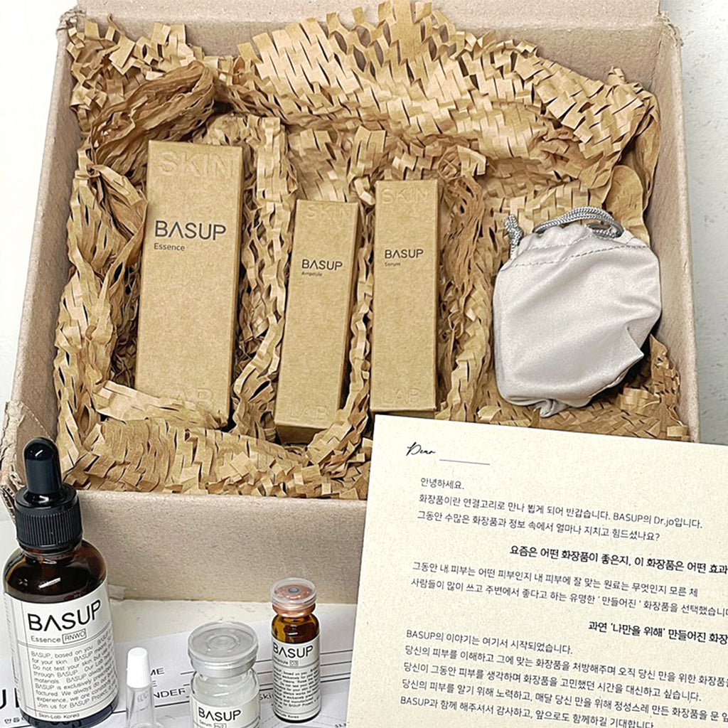 BASUP skincare gift set with three kraft product boxes and a white drawstring pouch, with skincare bottles and a Korean-language note in front.