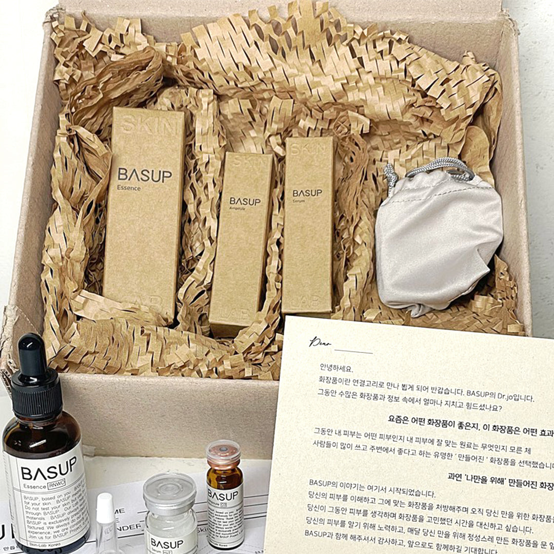 BASUP skincare gift set with three kraft product boxes and a white drawstring pouch, with skincare bottles and a Korean-language note in front.